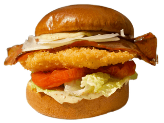 Csirkés schnitzel szendvics. Rántott csirkemell brioche buciban, baconnel, római salátával, Caesar-öntettel, paradicsommal és parmezánnal