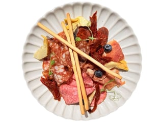 Plate of cold cuts. Parma ham, Spanish fermented salami, spicy Hungarian sausage served with sun dried tomatoes,  artichokes and grissini