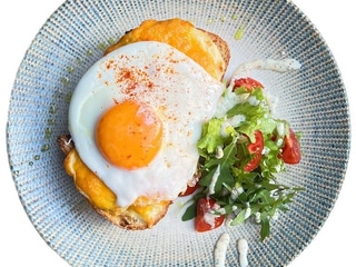 Croque Madame Sandwich. Prosciutto cotto, cheddar sajt és besamelmártás kovászos kenyéren, tükörtojással és mini salátával tálalva