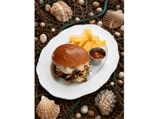 Burger z grillowanym mięsem z muli, sosem parmezanowym, pomidorkami daktylowymi i rukolą, podawany z frytkami