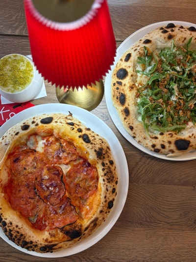 Folks pizzas at a table with a red lamp