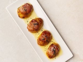 Картопля в свинячій сітці з беконом і пряним маслом