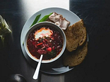 Borsch com banha de porco, cebolinho e pedaço de pão fermentado