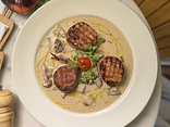 Grilled pork medallions in pancetta with creamy - mushroom sauce