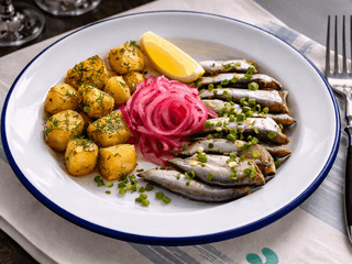 Тюлька з печеною картоплею, зеленою цибулькою і пряним маслом