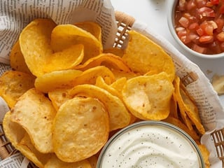 Košík chipsů podávaných s rajčatovou salsou a omáčkou dle výběru.