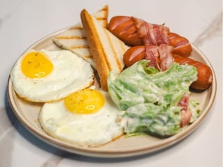 Яєшня з молочною сосискою, беконом, хрустким салатом та тостами