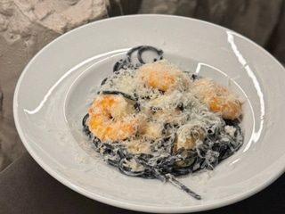 Паста з чорнилами каракатиці, креветками та мідіями в мушлях у вершковому соусі